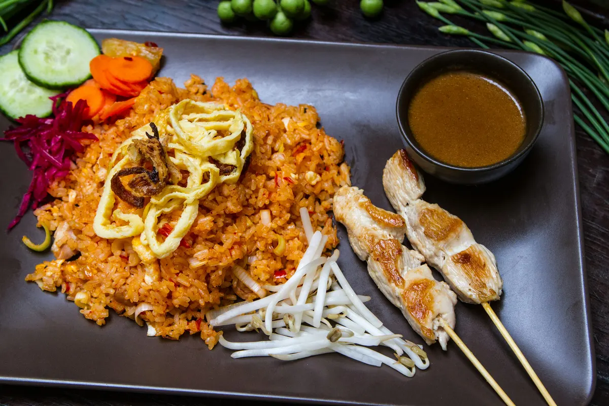 Rice, skewered meat and vegetables on a dark plate